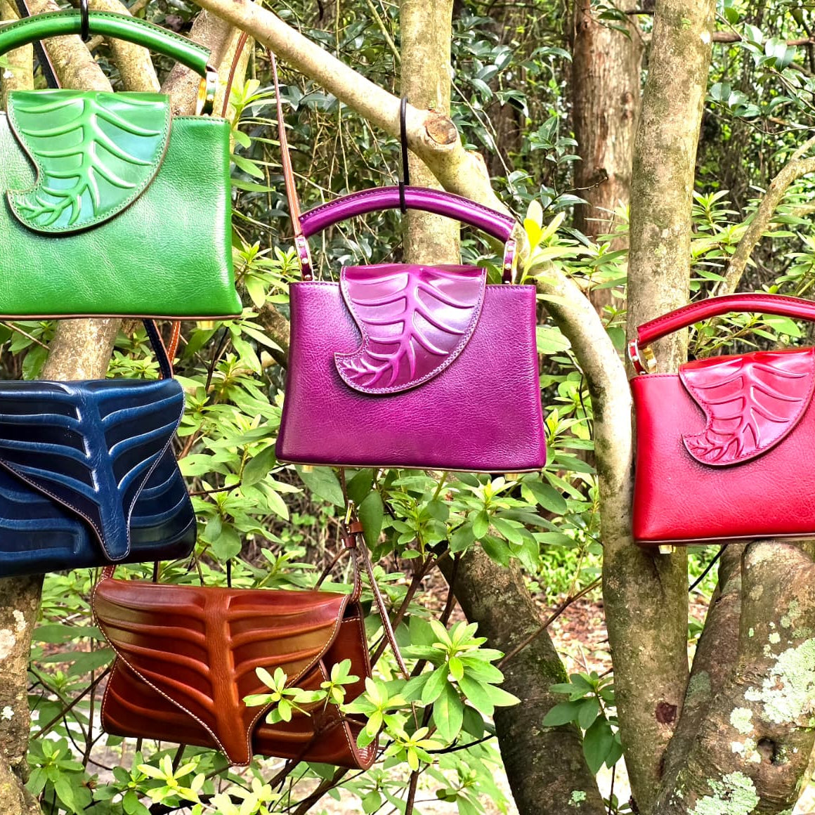 Colorful handbags hanging on a tree branch in a forest setting